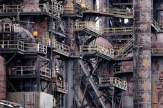 an old factory building with lots of rusty pipes and ladders on it's sides