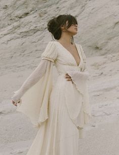 a woman in a white dress standing on the beach