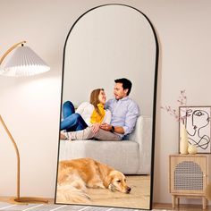 a man and woman are sitting on a couch with a dog in front of them