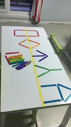 a white table with colored crayons on it in front of an open window