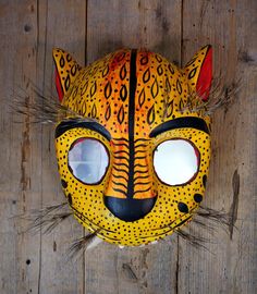 a yellow and black cat mask sitting on top of a wooden floor