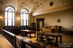 an empty courtroom with desks and chairs in the center, looking out to the other side