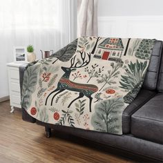 a couch covered in a blanket with an image of a deer and trees on it