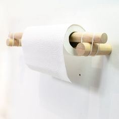 a roll of toilet paper is hanging on the wall with two wooden dows attached to it