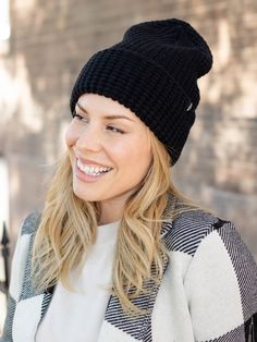 a smiling woman wearing a black knitted hat