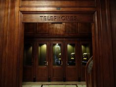 an entrance to a building with wooden paneling and glass doors that read telephones