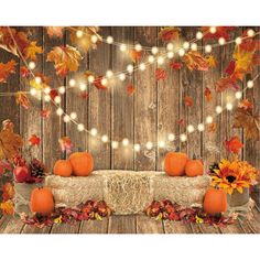 an autumn scene with pumpkins and fall leaves on a wooden table surrounded by lights