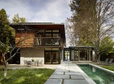 a house with a pool in front of it and some chairs around the outside area