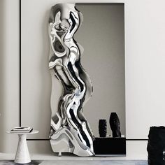 a large mirror sitting on top of a white floor next to a black and white sculpture