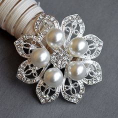 a white flower brooch with pearls on it