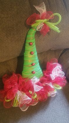 a green christmas tree hat with red and yellow bows sitting on top of a couch