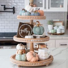 three tiered trays filled with pumpkins and gourds on top of a kitchen counter