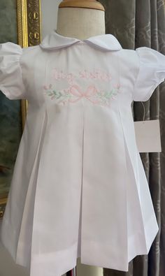 💕This beautiful dress is perfect for all occasions; including but not limited to Big/Little Sister, graduation, Baptism, Easter, dedications, 1st birthdays.  💕The quality of this dress is amazing, it is made out of cotton pique, and can become an heirloom to pass to future generations!  💕Customize this piece by adding monogram, initials, design or your child's handwriting. The possibilities are endless.  I would love to create this special piece for you and your little one. ❤️Disclosure: I ca White Cotton Dress With Pleated Bodice, White Fitted Dress With Box Pleat, Cute Fitted Dress For First Communion, Classic Short Sleeve Dress For Baptism, Pink Fitted Dress For Confirmation, Cute Fitted Pleated Dress, Short Sleeve Ruffled Dress For Confirmation, White Short Sleeve Dress With Pleated Hem, Cute Short Sleeve Baptism Dress