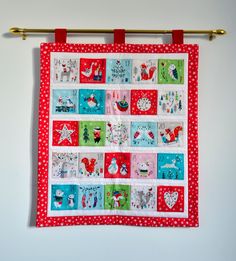 a red and white quilt hanging on a wall next to a metal rod with polka dots