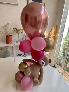 a teddy bear sitting on top of a table with balloons