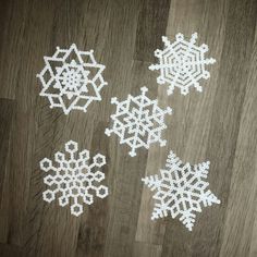 four snowflakes made out of beads on a wood floor