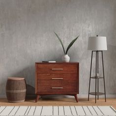 a wooden dresser sitting next to a lamp on top of a hard wood floor in front of a gray wall