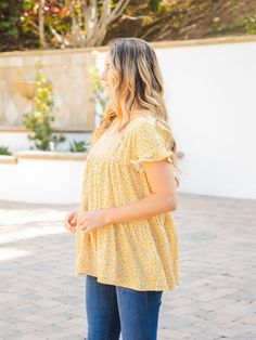 Introducing the Michelle Babydoll Top - Yellow, the perfect addition to your wardrobe! This top is designed with layers of the softest fabric and features patterns that will make you swoon. The flowy and fun design of this top ensures that you'll create a charming look in no time. Crafted with a babydoll fit, the Michelle top is designed to flatter your figure without overwhelming your overall look. Available in sizes Small (0-4), Medium (6-8), Large (10-12), and XL (12-14), you're sure to find Cute Flowy Tops For Spring, Cute Flowy Summer Tops, Flowy Short Sleeve Breezy Top, Casual Tiered Tops For The Beach, Flowy Short Sleeve Tops For Spring, Flowy Cotton Top For Layering, Tiered Tops For Spring Vacation, Cute Flowy Ruffled Tops, Casual Flowy Printed Top