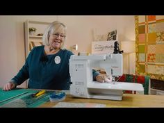 an older woman sitting at a table with a sewing machine on it's side