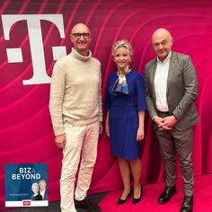 three people standing next to each other in front of a pink wall with the letter f on it