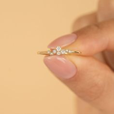 a woman's hand holding a gold ring with three small white diamonds on it