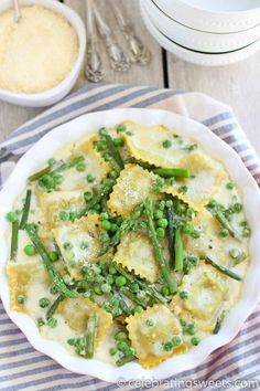 a white bowl filled with ravioli and asparagus on top of a table