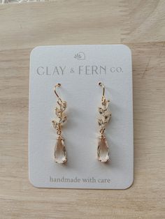 a pair of gold tone earrings with clear stones