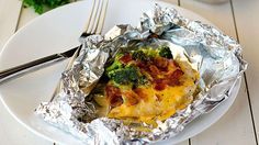 a white plate topped with an omelet covered in bacon and broccoli