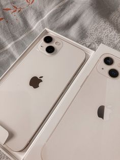 two new iphones in their boxes on a bed