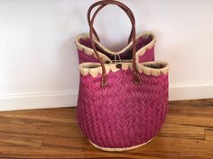 These beautiful pieces are designed in South Africa. Handmade with raffia and featuring leather handles, these bags bring the perfect mix of bohemian chic to everyday wear! Capable of being used as a handbag, basket or storage-this multi-purpose piece is a cannot miss! The double closure top provides a multi-style capability as well! Sizing: 16 inches wide x 12 inches deep x 13 inches high Pink Top Handle Straw Bag For Beach, Pink Bucket Bag With Braided Handles For Shopping, Pink Bucket Bag With Braided Double Handles, Pink Bucket Bag With Double Braided Handles, Pink Bucket Bag With Braided Handles And Top Handle, Pink Double Handle Bucket Bag With Braided Handles, Pink Top Handle Straw Bag For Everyday, Pink Travel Bag With Bamboo Handle, Pink Vacation Bag With Bamboo Handle