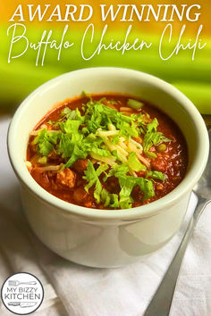 a white bowl filled with chicken chili and garnished with cilantro leaves