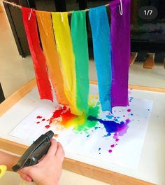 someone is using scissors to paint the rainbows on paper with colored watercolors