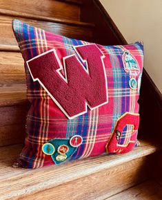 a red pillow with the letter w on it sitting on some stairs next to a stair case