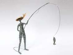 a wire figurine holding a fishing rod and a fish on a white background