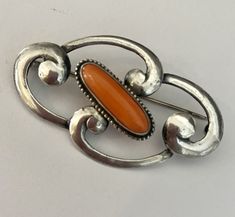 Fabulous! Beautiful sterling silver swirls define the the Art Nouveau era. The centerpiece of this brooch is an elongated cabochon natural coral. This brooch looks gorgeous pinned on a simple velvet choker.  Marked STERLING Elegant Orange Brooch Jewelry, Elegant Sterling Silver Brooch With Cabochon, Orange Brooch Jewelry For Formal Occasions, Formal Orange Brooch Jewelry, Elegant Oval Sterling Silver Brooches, Elegant Orange Brooches For Gifts, Velvet Choker, Natural Coral, Tatting