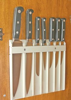 there are many knives hanging on the wall in this kitchen rack that is made out of white plastic