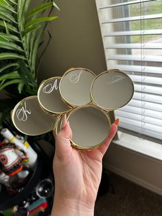 a person holding four mirrors in front of a window with the word monogram on them