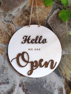 a sign that says, hello we are open hanging on a stone wall with ivy