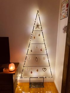 a christmas tree with lights on it in a living room next to a wall mounted television