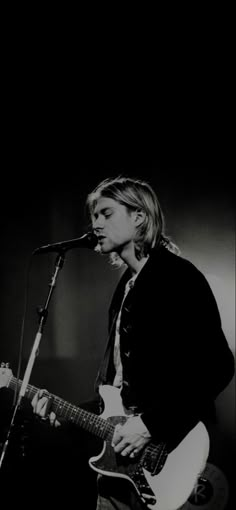 a man that is playing a guitar in front of a microphone