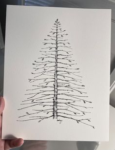 a hand holding up a card with a christmas tree drawn on the inside of it