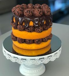 there is a cake that has chocolate frosting on the top and yellow bottom, sitting on a white pedestal