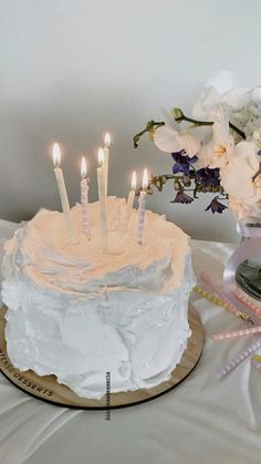 a cake with white frosting and lit candles