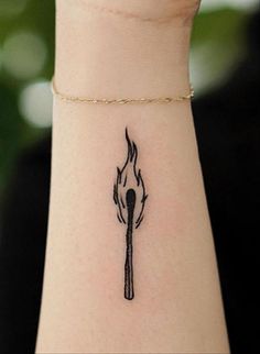 a woman's wrist with a black and white fire tattoo on the left side of her arm