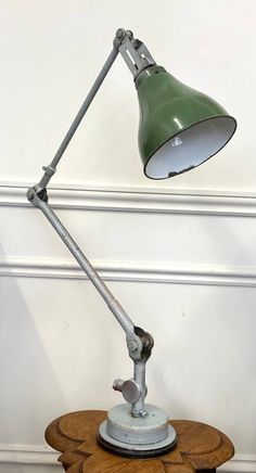 an old desk lamp is sitting on top of a wooden table in the corner of a room