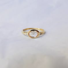 a close up of a gold ring on a white surface with a small diamond in the middle