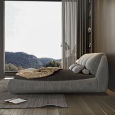 a large bed sitting on top of a hard wood floor next to a tall window