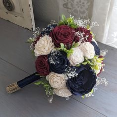 a bridal bouquet with red, white and blue flowers on a wooden floor in front of a door