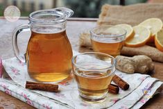 two glasses of tea sit on a table with lemons and cinnamon