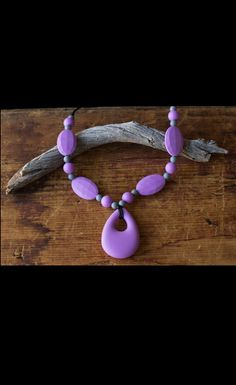 a necklace with purple beads on a wooden table